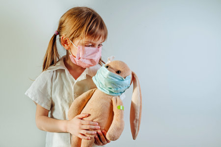 Unrecognizable little girl wearing medical gown holding soft toy bunnyの写真素材