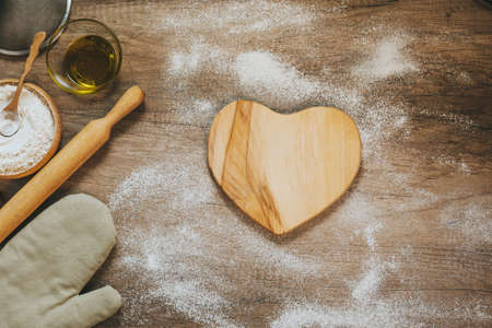 Heart shape wooden board near ingridients for prepairing doughの写真素材