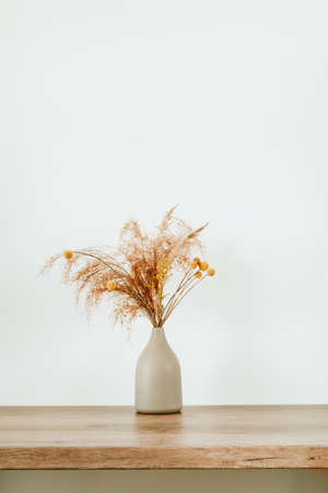 Dried flowers pampas grass in the ceramic vase on the wooden table with blank space for text. Detail of cozy minimalictic home interior.の写真素材