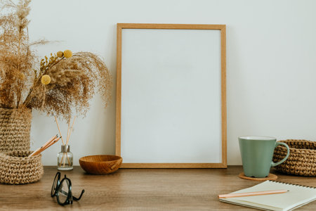 Empty wooden picture frame and dried flowers pampas grass in the jute vase on the wooden table with...
