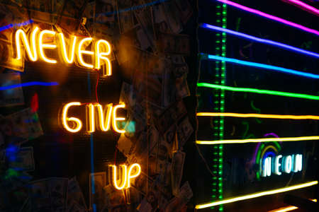 Colorful neon lights background with sign NEVER GIVE UP and NEON. selective focus.の写真素材
