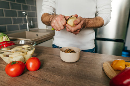 man peeling potatoes. Unrecognizable man cooking vegetables in the kitchen. Close up of males hands preparing potato for cook. selective focus.の写真素材