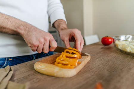 Man peeling bell pepper. Unrecognizable man cooking vegetables in the kitchen. Close up of males...