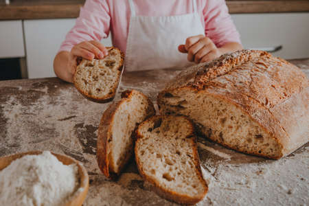 Unrecognizable little girl in apron holding a slice of homemade whole grain bread. selective focus.の写真素材