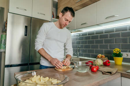 Man cutting potatoes on the board. Young man cooking vegetables in the kitchen preparing potatoes. selective focus.の写真素材