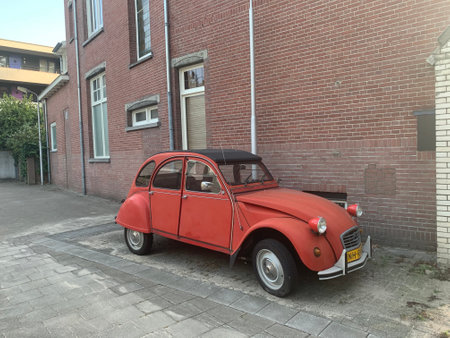 Old vintage red Citroen 2 cv car parked in the backyard. Tilburg, North Brabant / Netherlands.