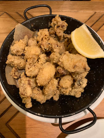 Fried baby squid dish in tempura with lemon in a skillet, casserole. It is a traditional Spanish and...
