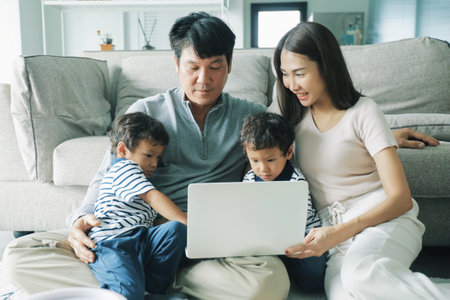 Happy asian family using laptop computer while sitting on sofa at home