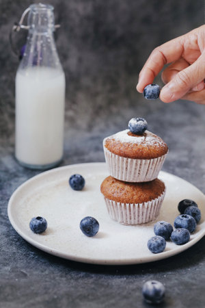Fresh blueberry muffins on a plate with a cup of milk