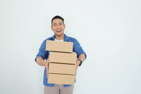 Young asian man carrying a stack of cardboard boxes on white background