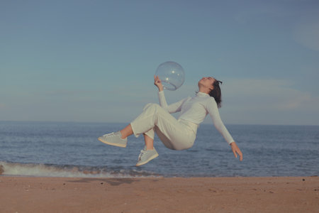 young beautiful and happy Asian Chinese woman in white sport suit jumping on beach holding big...