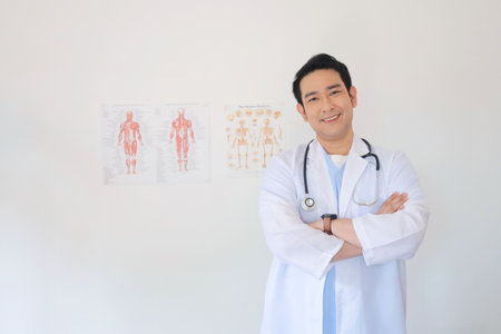 Portrait of a young Asian male doctor standing with arms crossed.の写真素材