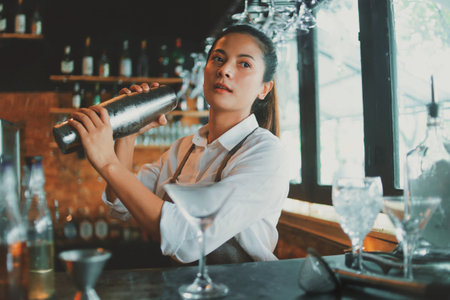 young beautiful asian woman using shaker for making cocktail in barの写真素材