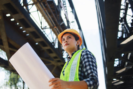 Portrait of female engineer or architect with blueprint at construction site.