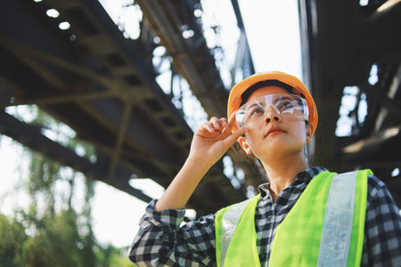 Portrait of Asian female engineer wearing safety helmet and safety vest working on construction site.の写真素材