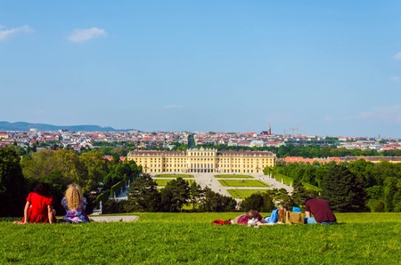 Tourists enjoying and relaxing with beautiful view of palace in park, Vienna, Austriaの素材