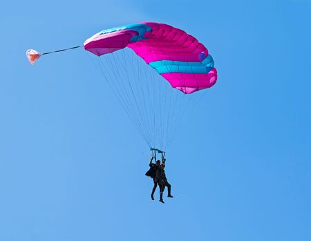 Pair of skydivers on a blue sky background. Tandem parachuting. Canopy in the sky.の写真素材
