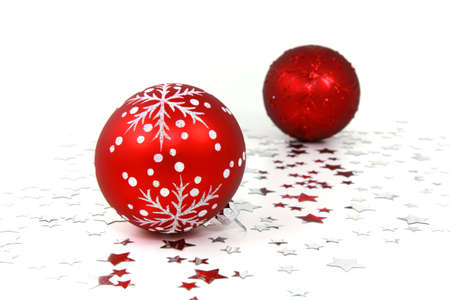 Two red glass christmas baubles on white background with silver starsの写真素材