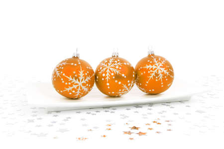 orange baubles on a plate with stars on the backgroundの写真素材