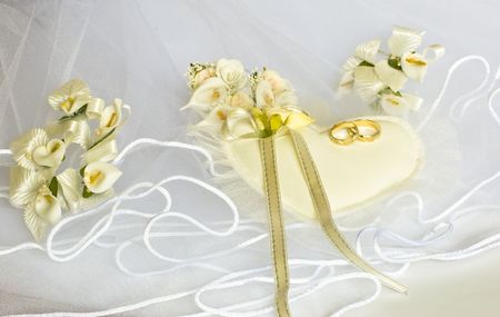 wedding rings and flowers decorations over bridal veil