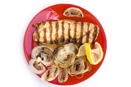 Grilled chicken breasts with onion and lemon in a plateの写真素材