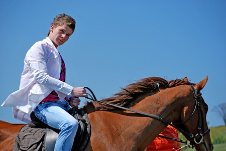 young and attractive man riding brown horseの写真素材