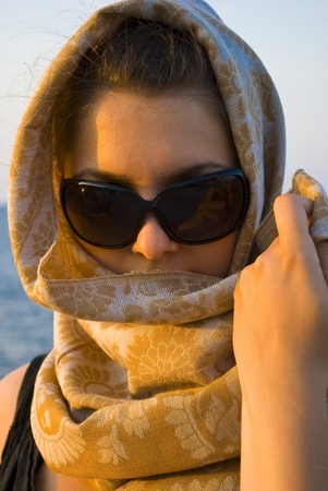 beautiful young woman posing with scarf on sunset near seaの写真素材
