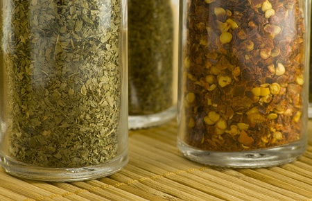 different spices in glass jars on wooden matの写真素材