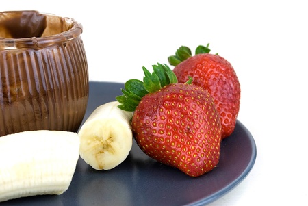 delicious strawberries and bananas covered with chocolate in a grey plateの写真素材