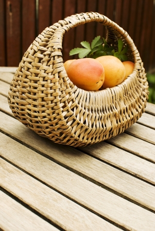 Fresh apricots in basket over wooden tableの写真素材