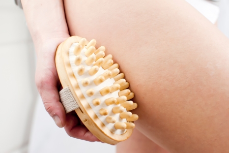 young woman making massage with wooden massager to prevent celluliteの写真素材