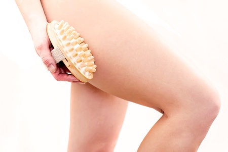 young woman making massage with wooden massager to prevent celluliteの写真素材