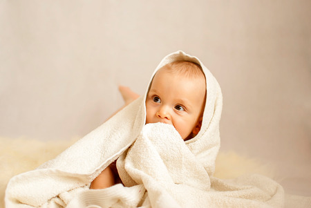 portrait of a happy caucasian adorable baby boy with blanketの写真素材