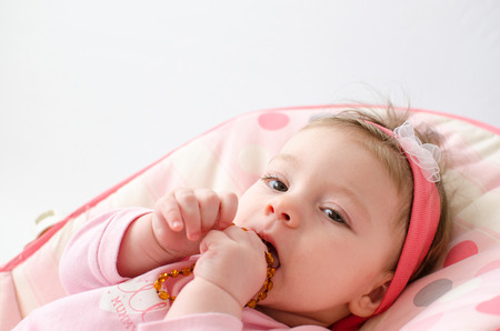 beautiful baby girl chewing amber teething necklaceの写真素材