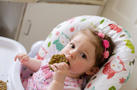 baby led weaning girl eating grilled chicken meatballs for lunchの写真素材