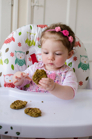 baby led weaning girl eating grilled chicken meatballs for lunchの写真素材