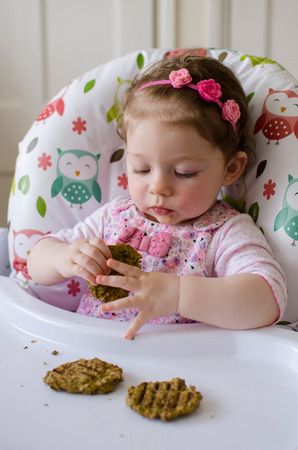baby led weaning girl eating grilled chicken meatballs for lunchの写真素材