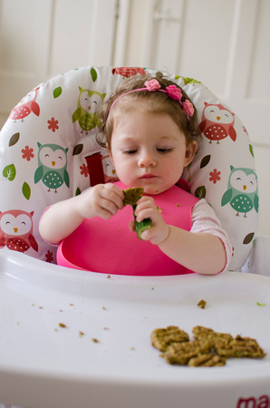 baby led weaning girl eating grilled chicken meatballs for lunchの写真素材