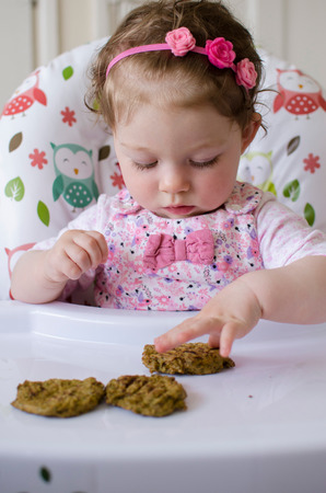 baby led weaning girl eating grilled chicken meatballs for lunchの写真素材