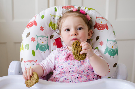 baby led weaning girl eating grilled chicken meatballs for lunchの写真素材