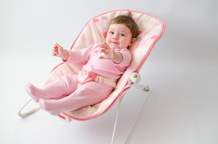 beautiful happy baby girl in a bouncer wearing pinkの写真素材