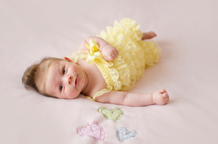 adorable two months old baby girl lying on her back on a pink blanketの写真素材
