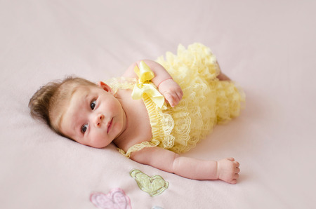 adorable two months old baby girl lying on her back on a pink blanketの写真素材