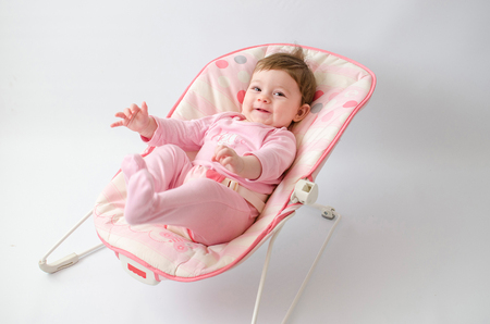 beautiful happy baby girl in a bouncer wearing pinkの写真素材