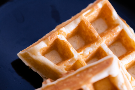 woman hands prepare waffle for serving process.waffle made from dough and batter.tasty dessert sweets waffle served on daylight in cafe bokeh background.waffle with strawberry on black plate.の写真素材