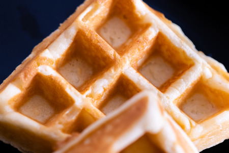 woman hands prepare waffle for serving process.waffle made from dough and batter.tasty dessert sweets waffle served on daylight in cafe bokeh background.waffle with strawberry on black plate.の写真素材