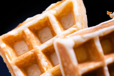 woman hands prepare waffle for serving process.waffle made from dough and batter.tasty dessert sweets waffle served on daylight in cafe bokeh background.waffle with strawberry on black plate.の写真素材