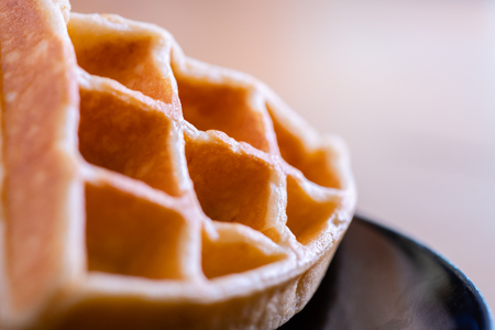woman hands prepare waffle for serving process.waffle made from dough and batter.tasty dessert sweets waffle served on daylight in cafe bokeh background.waffle with strawberry on black plate.の写真素材