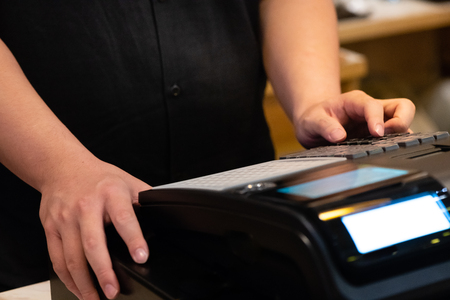 cash register installed on counter for accepting order from customer.sales man entering amount on electronic cash register in coffee shop and retail store.restaurant cashier typing on cash register.の写真素材