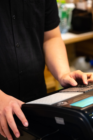 cash register installed on counter for accepting order from customer.sales man entering amount on...